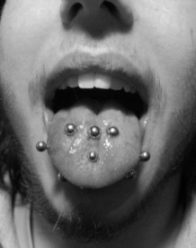 „Jazyk s klasickým i horizontálním piercingem a venomy.“ Zdroj: Hell.cz