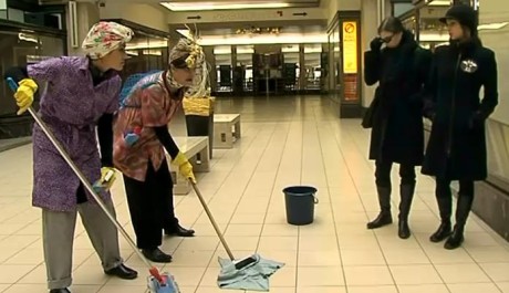 "Kolemjdoucí opovržlivě sledují dvě uklizečky."