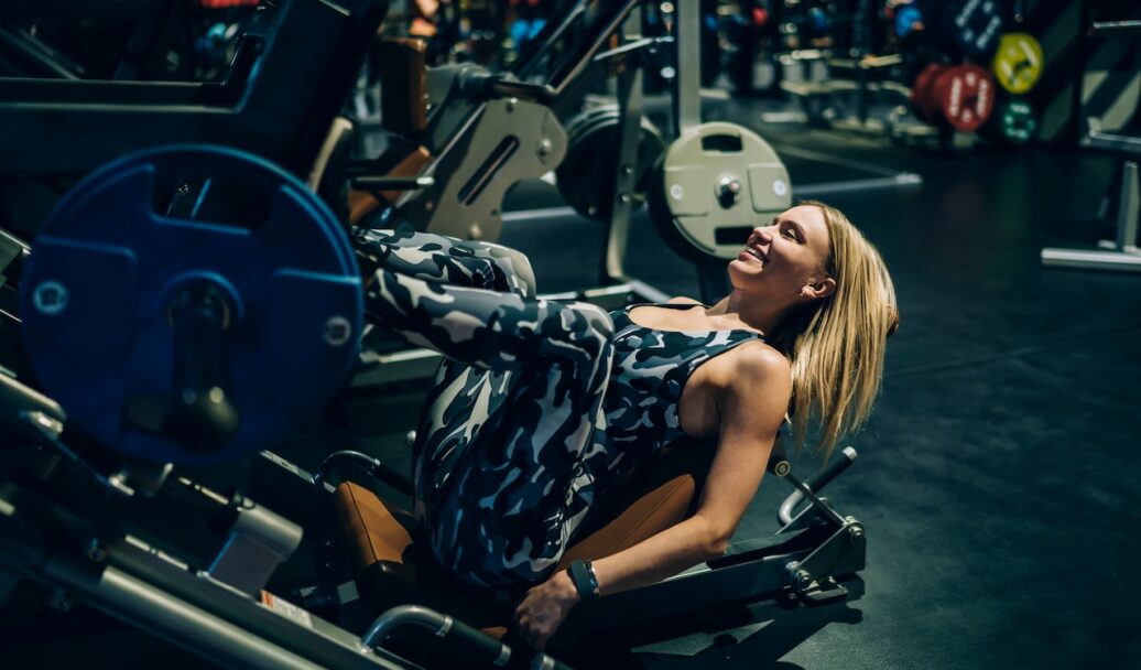 Cheerful blonde woman lifting weights with legs