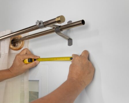Worker repairman hanging and fixing the curtain on the window
